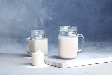 Mason jars with protein shake and scoop of powder on table