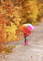 Little girl with umbrella taking walk in autumn park on rainy day