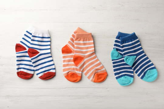 Cute child socks on white wooden background, top view