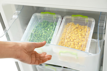 Woman opening refrigerator drawer with frozen vegetables, closeup