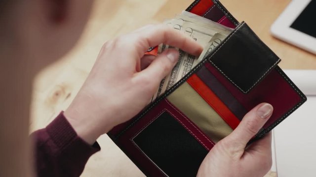 Woman counting cash money in her wallet.
