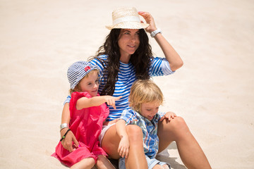 Beautiful mother, son and daughter sitting on the ocean.