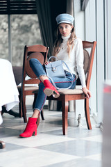 Photo of a young, beautiful girl in bright colors. Girl sitting on a chair. Fashionable toning in gray tones. Toned image.