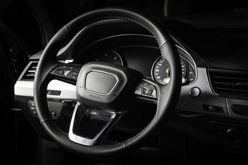 Obraz na płótnie Canvas Dark luxury car interior. Black leather multifunctional steering wheel, start and stop engine buttom, dashboard