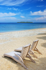 Sun chairs on white sandy beach