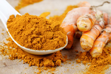 Turmeric roots and powder herb on wooden background.