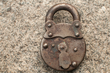 Old weathered grunge retro locked padlock closeup on solid stone surface background