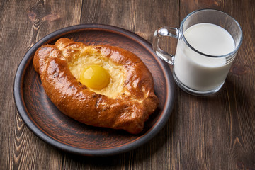 Caucasian kitchen. Khachapuri with the egg and cheese, glass cup with milk.