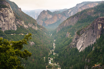 Fototapeta na wymiar Aerial view of Merced river flowing from Yosemite Valley; Brideveil Falls visible in the background; smoke from Ferguson Fire present in the air and covering the sky; Yosemite National Park, CA