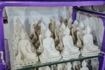 Drying unbaked small clay Buddha statues after molding in workshop