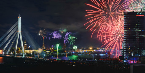 Colorful fireworks over river Daugava on Latvia's 100th birthday. Independence day celebration in Riga city with panoramic view over the old town and cable bridge. Light show in Riga city.