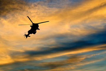 Fototapeta na wymiar Silhouette of a flying helicopter against the bright evening sky