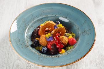 Dried apples with ground pistachios, garnished with forest fruits and molten chocolate