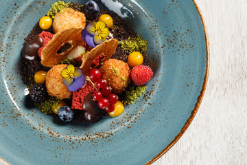 Dried apples with ground pistachios, garnished with forest fruits and molten chocolate