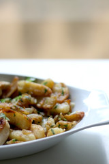 Roasted chicken and Lyonnaise potatoes. Lyonnaise potatoes are sliced pan-fried potatoes with onion, parsley, butter and garlic. Selective focus.