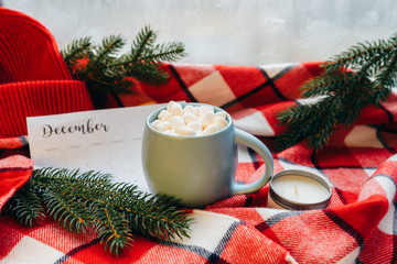 Calendar December month. Christmas concept. Coffee cup with marshmellow and holiday decoration on the plaid background.