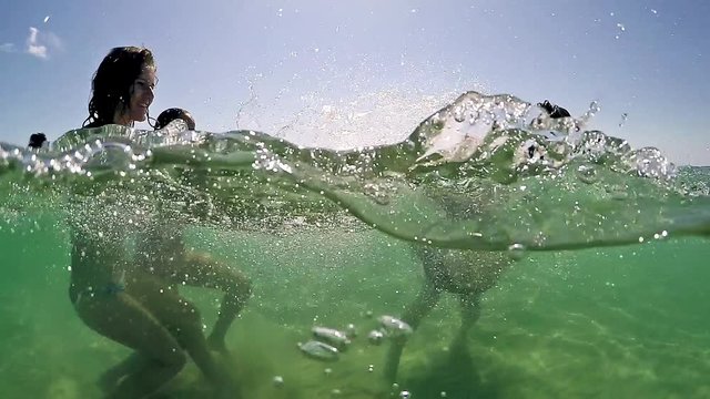 Portrait of people splashing on each other in the lake, gopro dome half underwater view, SLOW MOTION