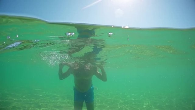 Young teen male go standing on father shoulders, gopro dome half underwater view