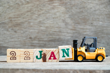 Toy forklift hold block N to complete word 22jan on wood background (Concept for calendar date in 22 month January)