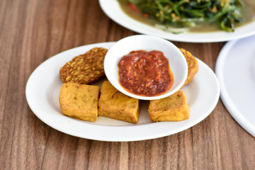 Baceman. Fried food dish of sweet-soy braised bean curd, tempeh, and offal. Popular side dishes in Javanese meals. Served on woven bamboo plate.