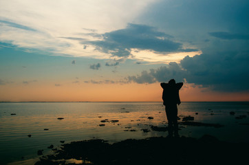 silhouette of a woman at dusk on the beach against the late sunset