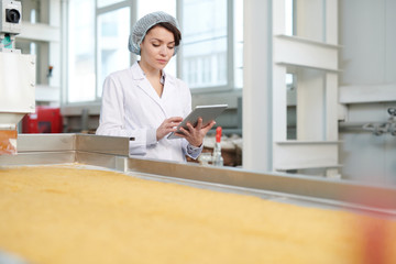 Waist up portrait  of  female worker worker doing  production quality inspection in food factory...