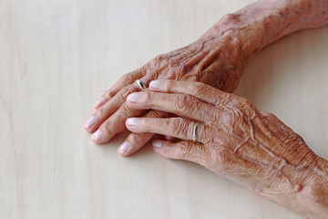 Die Hände einer sehr alten Frau auf einem Holztisch