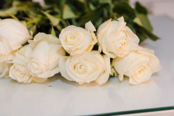 Obraz na płótnie Canvas White roses lie on a bright table. Beautiful white flowers.