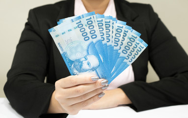 Close-up business woman wearing suit holding chilean money notes. Chile ten thousand (10000) pesos. Selective focus.