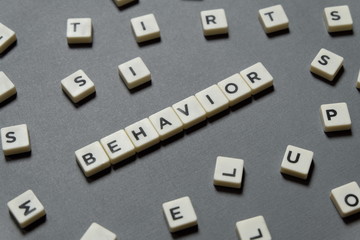 Behavior word made of square letter word on grey background.
