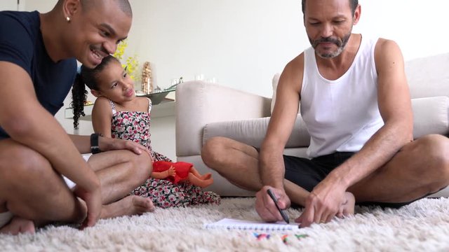 Gay Family with Adopted Child Drawing on Notebook at Home