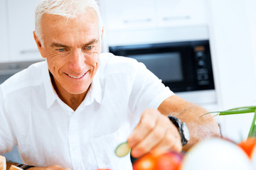 Portrait of a smart senior man cooking in kitchen