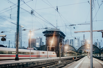 Fototapeta na wymiar Zug fährt bei Dämmerungen durch den Bahnhof einer Großstadt
