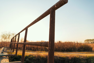 Fototapeta premium Bridge over an irrigation channel of the Lomellina at sunset