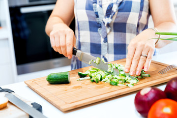 Female hands cutting cucumbers