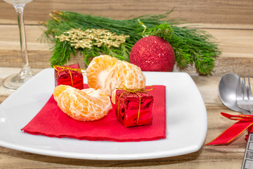 Christmas table place setting. Festive background. Branches of fir, balls, cutlery and tangerines. Close-up.