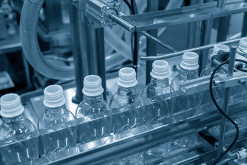 The new plastic bottles on the conveyor belt at the drinking water factory. Drinking water manufacturing process.