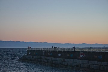 Victoria, British Columbia, Canada: Ogden Point Breakwater (1916) with the Strait of Georgia behind it and the mountains of Olympic National Park (Washington, USA) in the distance, at sunset.