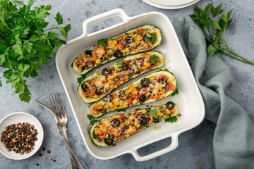 Stuffed zucchini boats with vegetables ( tomato, pepper, corn, red onion and olives) and cheese in...