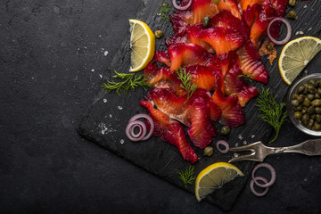 sliced Gravlax,  scandinavian beet cured salmon  served with red onion, capers and lemon