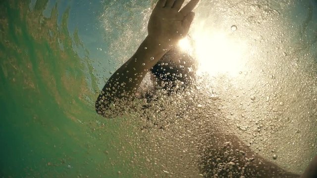 Snorkeling man makes bubbles defending from a shark attack, underwater shark pov with sunset sun rays from surface