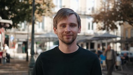 Image of handsome young man walking on the street and looking at camera close up portrait