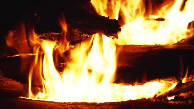 Closeup view of burning firewoods, firecamp with sparks and black pot above it