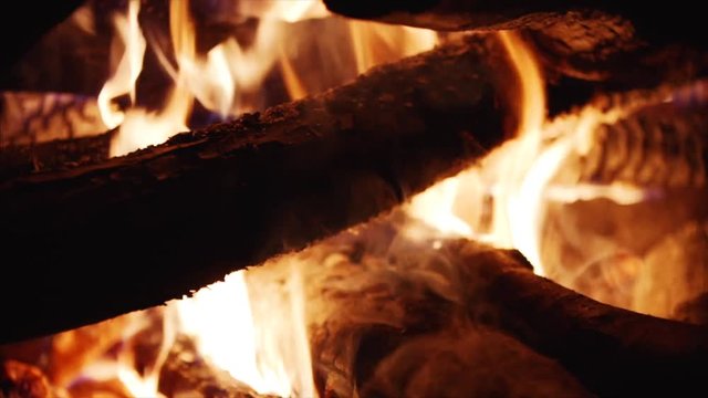 Close up and slow motion view of burning firewoods, bright firecamp with sparks