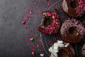 baked chocolate donuts with various topping, top view, dark background