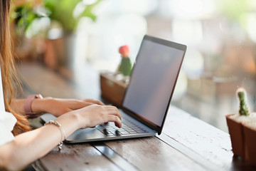 Cropped shot businesswoman hand working on a laptop at desk in cafe.