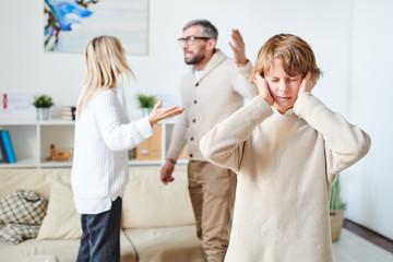 Distraught teenage son in sweater suffering from parents conflict: he keeping eyes closed and...