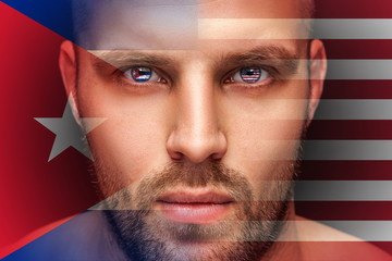 A portrait of a young serious man, in whose eyes are reflected the national flags of America and...