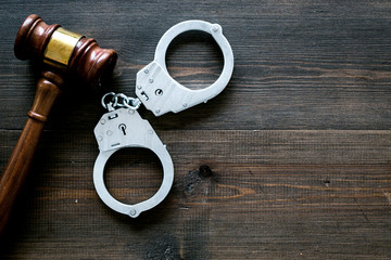 Arrest concept. Metal handcuffs near judge gavel on dark wooden background top view copy space