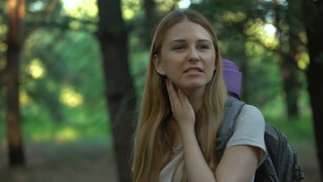 Lady suffers from mosquitoes bite while camping, killing bug with hand, itching